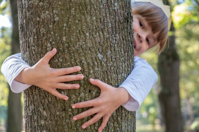 gestes écologiques pour les enfants - Une petite fille fait un câlin à un arbre