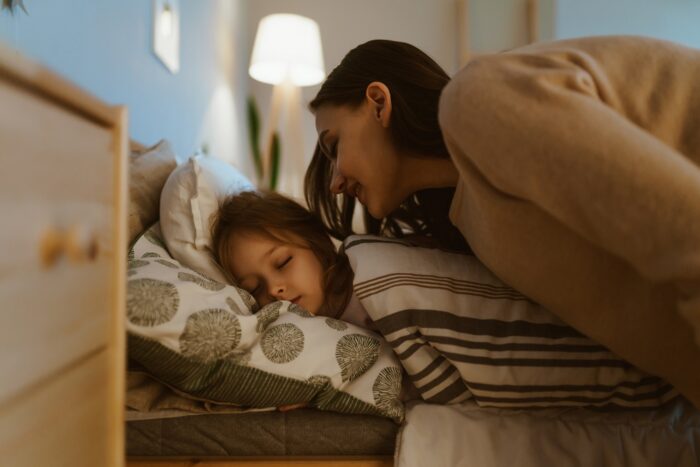 maman qui chante une chanson à sa petite fille qui s'endort dans son lit