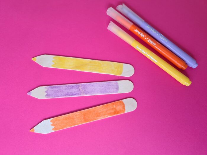 Trois marque-pages crayon coloriés en jaune, violet et orange au feutre Maped