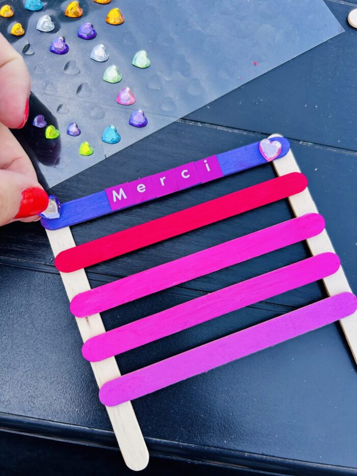 Décoration du porte-bijoux avec des strass cœur et un message Merci en stickers lettres