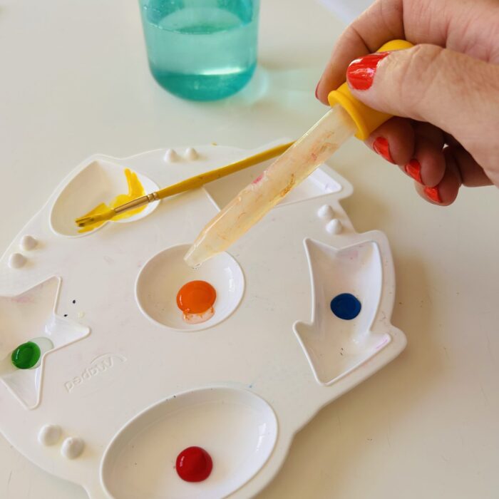 Enfant mélange de la gouache avec un peu d'eau dans une palette pour la peinture soufflée