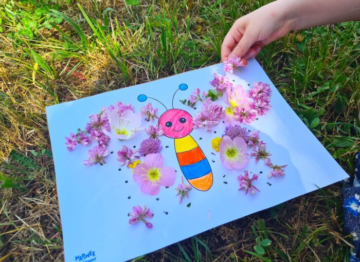Main d'enfant déposant une fleur rose sur le modèle papillon du tableau floral